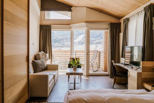 a hotel room with a bed and a desk and a couch at Hotel Lac Salin Spa & Mountain Resort in Livigno