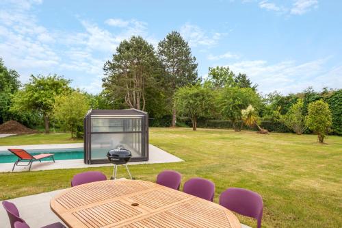 une maison en verre avec une table et des chaises dans une cour dans l'établissement Green Lodge - Piscine chauffée et grand Jardin à proximité des Plages de Pléneuf Val-André, à Saint-Alban