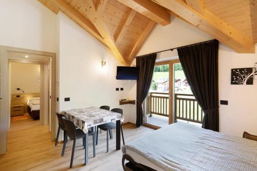 1 dormitorio con mesa, sillas y balcón en Appartamento Salient Casa Campacc en Livigno