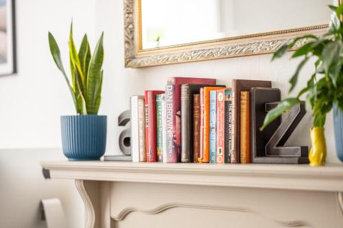 a shelf of books on a table with a potted plant at Lyme Townhouse in Lyme Regis