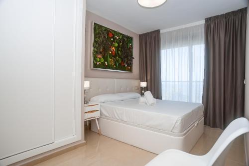 a white bedroom with a bed and a window at Holiday Deluxe Apartment Miramar Magic World in Oropesa del Mar