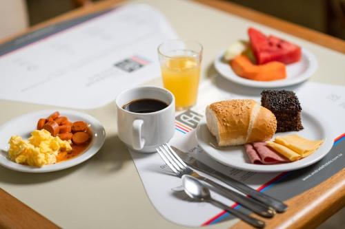 uma mesa com pratos de comida para o pequeno-almoço e uma chávena de café em Rede Andrade Onda Mar no Recife