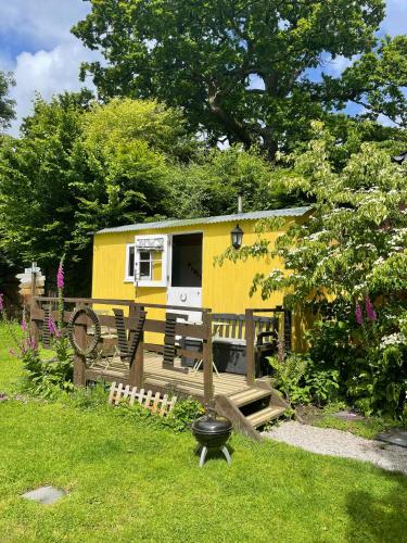a yellow tiny house in a garden at The Hideaway at Duffryn Mawr Self Catering Cottages in Cowbridge
