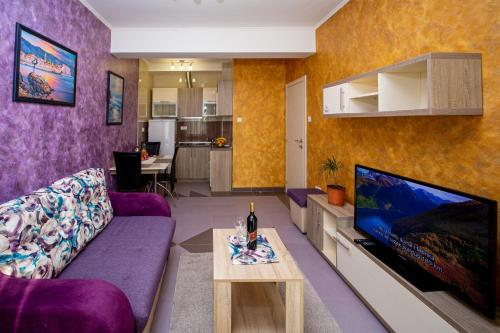 a living room with a purple couch and a tv at SunSea Apartments in Budva