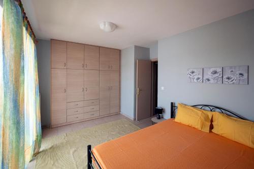 Schlafzimmer mit einem orangefarbenen Bett und Holzschränken in der Unterkunft Cozy Apartment St John in Chalkida