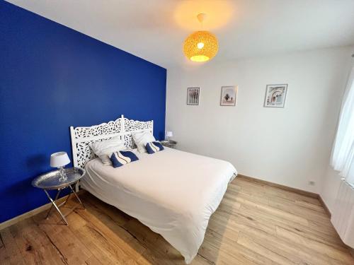 - une chambre bleue avec un lit blanc et un mur bleu dans l'établissement Le Prieuré, à La Rochelle