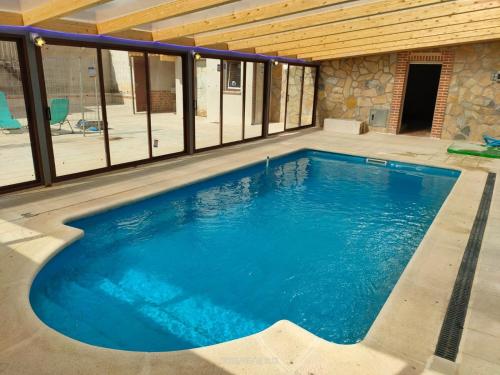 uma grande piscina numa casa com janelas em Casa Rural Baños del Rey con piscina climatizada em Vega de Santa María