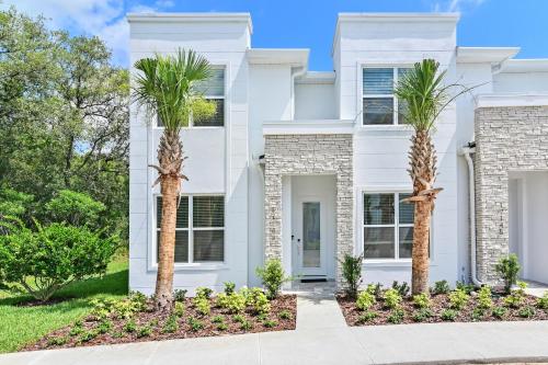 a white house with palm trees in front of it at New Spacious&Tranquil Townhouse near Disney in Orlando