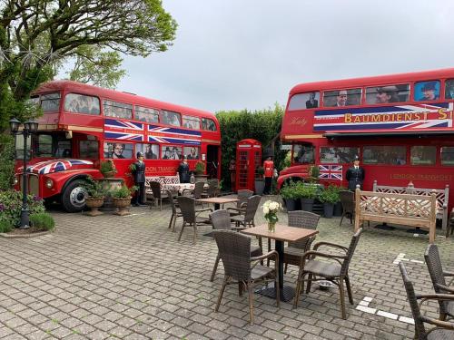 two red double decker buses parked next to tables at The Little Britain Inn Themed Hotel One of a Kind In Europe in Vettelschoß