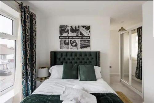 a bedroom with a large bed with green pillows at Penthouse Luxury Apartment in Dagenham