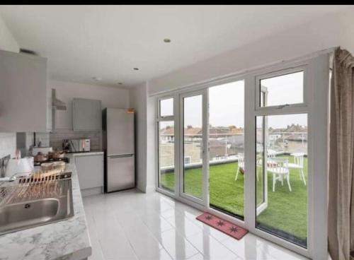 a kitchen with a large window with a view of a yard at Penthouse Luxury Apartment in Dagenham