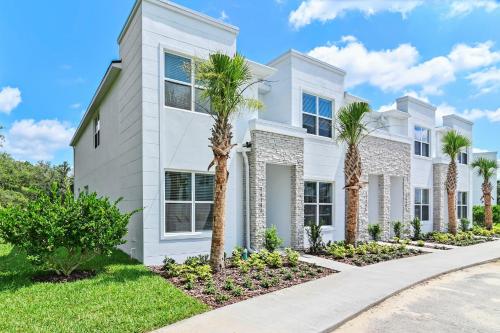 a white house with palm trees in front of it at New Spacious&Tranquil Townhouse near Disney in Orlando