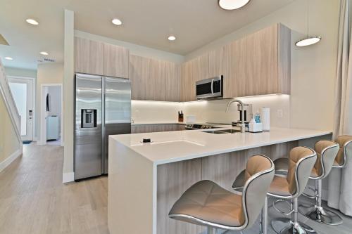 a kitchen with a large island with chairs and a refrigerator at New Spacious & Tranquil Townhouse near Disney - 4BR, 3FB, and Pool in Orlando