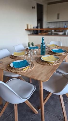 - une table en bois avec des chaises et une bouteille dans l'établissement Joli duplex au centre du Canon à quelques pas du Bassin, à Cap-Ferret