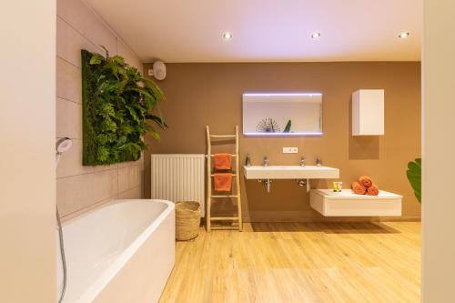 La salle de bains est pourvue d'une baignoire, d'un lavabo et d'un miroir. dans l'établissement La Grenouille - Suite de luxe & Welness Privatif, à Leuze-en-Hainaut