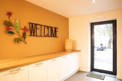 a kitchen with white cabinets and a welcome sign on the wall at La Grenouille - Suite de luxe & Welness Privatif in Leuze-en-Hainaut