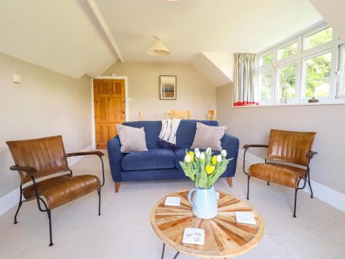 a living room with a blue couch and two chairs at Bodowen Coach House in Barmouth
