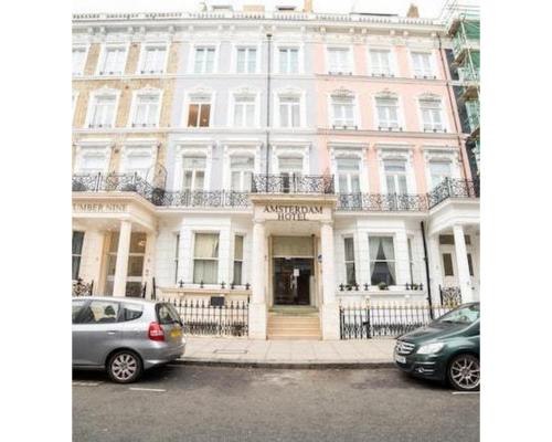 un edificio blanco con coches estacionados frente a él en Amsterdam Hotel en Londres