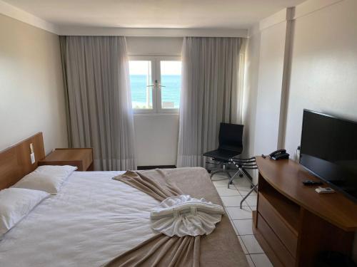 a bedroom with a bed and a desk and a television at Ponta Negra Flat ByHotéis in Natal