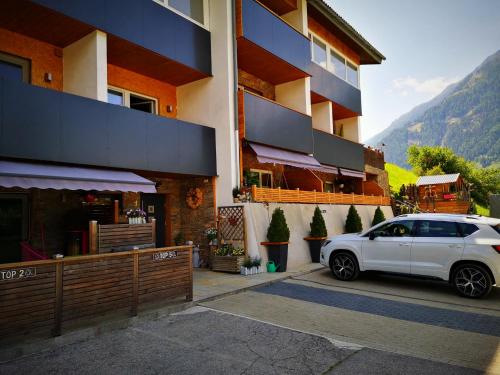 ein weißes Auto, das vor einem Gebäude parkt in der Unterkunft Haus Wibmer in Matrei in Osttirol