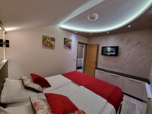 a bedroom with a large bed with red and white sheets at Apartman Prestige Jahorina in Jahorina