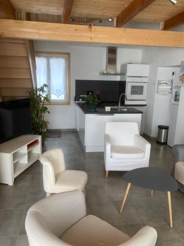 Il comprend un salon avec des chaises blanches et une cuisine. dans l'établissement Chez Léonce, à LʼÉpine
