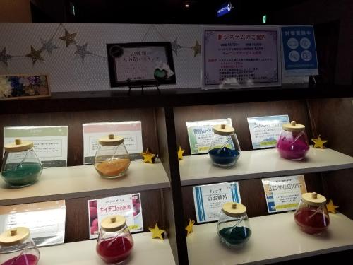uma exposição de diferentes taças coloridas em frascos de vidro em prateleiras em スタイリッシュ-大人専用 em Kameyama