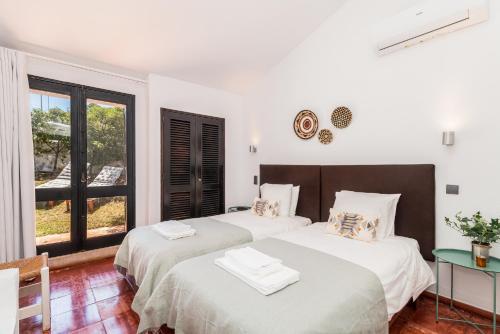 twee bedden in een witte kamer met een raam bij Casas Barulho - Villa Jacaranda A8 in Albufeira