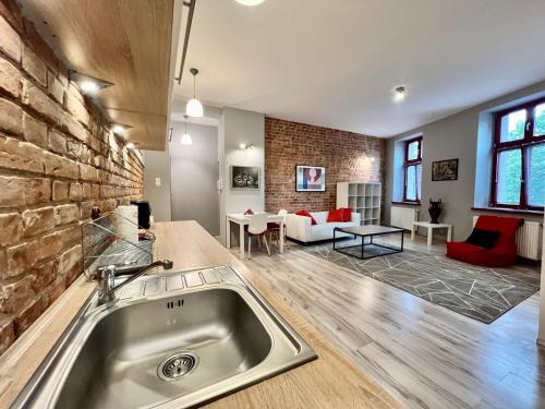 a kitchen with a sink and a living room at Red&Yellow Apartments Centrum in Olsztyn