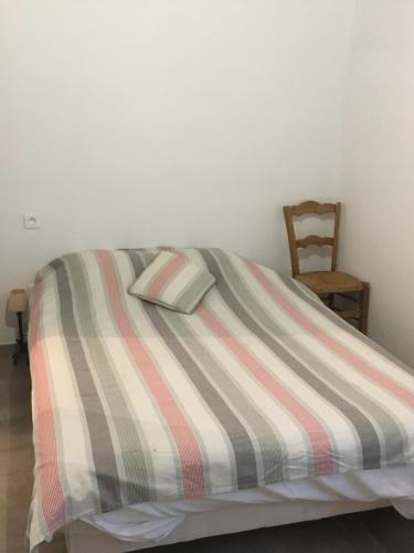 a bed with a striped comforter and a chair at Chez Léonce in LʼÉpine