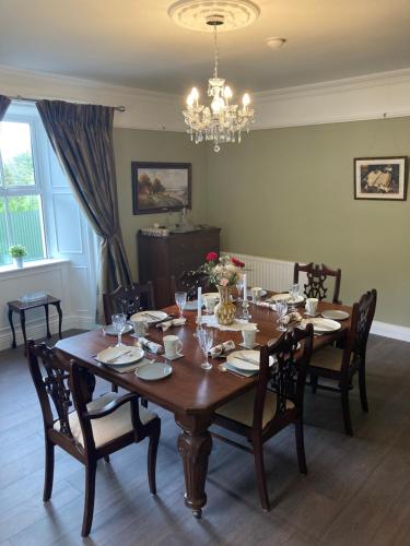 a wooden dining room table with chairs and a chandelier at Entire Farmhouse in Tipperary in Nenagh
