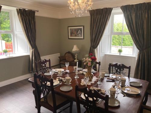 uma sala de jantar com mesa, cadeiras e janelas em Entire Farmhouse in Tipperary em Nenagh