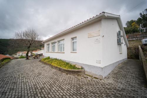a white building sitting on a brick road at Casas da Escola - "A Escola" - Meãs in Pampilhosa da Serra
