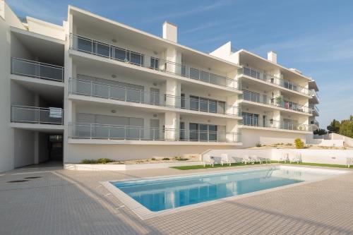 an apartment building with a swimming pool in front of it at Sunset Views - By SCH in Nazaré