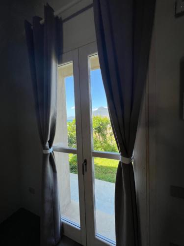 an open door with a window with blue curtains at ALELCA DOMO in Buggerru