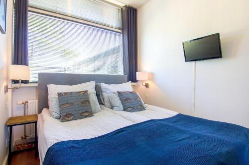 een slaapkamer met een bed met blauwe lakens en een raam bij Appartement De Zeemeermin, Free parking in Zandvoort