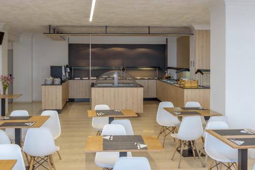 een restaurant met tafels en witte stoelen en een keuken bij Azure Mare Hotel in Chersonissos