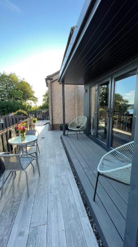 a wooden deck with two chairs and a table at Little bay cabin in Oban
