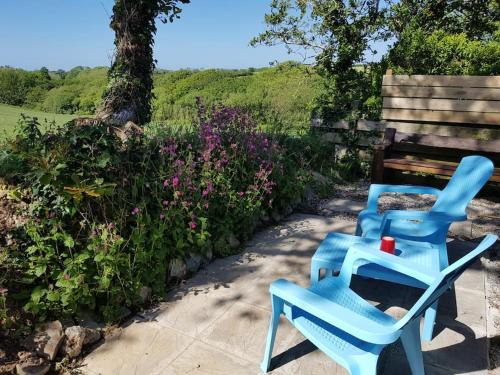 a pair of blue chairs sitting next to a bench at The Old Potting Shed with hot tub. Colan, Newquay. in Newquay