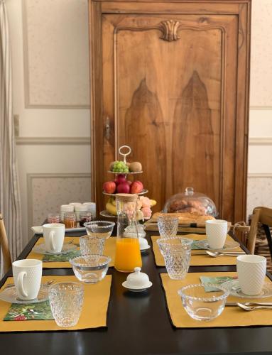 Una mesa de comedor con platos y vasos encima. en La Grenouillère - Chambre d'hôtes de charme, en Ballan-Miré
