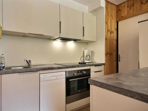 une cuisine avec des armoires blanches, un évier et une cuisinière dans l'établissement Bel appartement rénové, 3 chambres, proche pistes, parking, animaux acceptés - FR-1-455-25, à La Plagne
