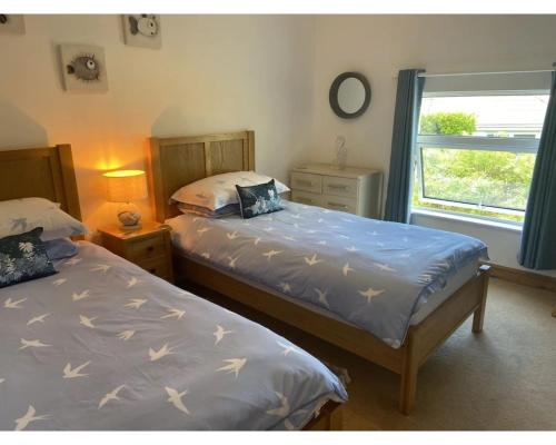 two twin beds in a room with a window at Higher Upover - Woolacombe-3 Bed-Sleeps 5-TJSHUO in Woolacombe