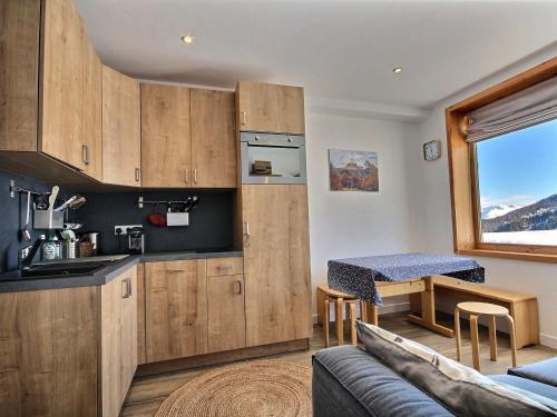 une cuisine avec des placards en bois et une table dans l'établissement Bel Appartement Rénové 4/5 Pers. Pied des Pistes à La Plagne Centre - FR-1-455-66, à La Plagne