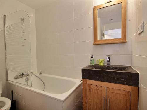 une salle de bain avec une baignoire, un lavabo et un miroir dans l'établissement Studio cabine rénové avec balcon, vue Mont-Blanc, pour 4 pers. à Aime 2000 - FR-1-455-80, à Aime La Plagne
