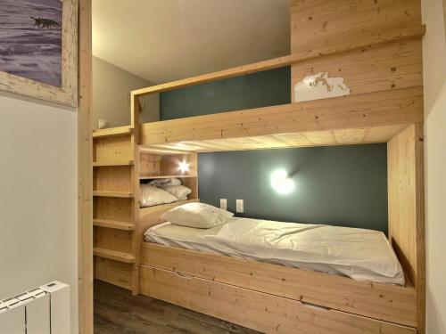 Cette chambre comprend un grand lit superposé en bois. dans l'établissement Spacieux 2 pièces avec accès pistes, terrasse, cheminée et parking - FR-1-455-147, à Aime La Plagne