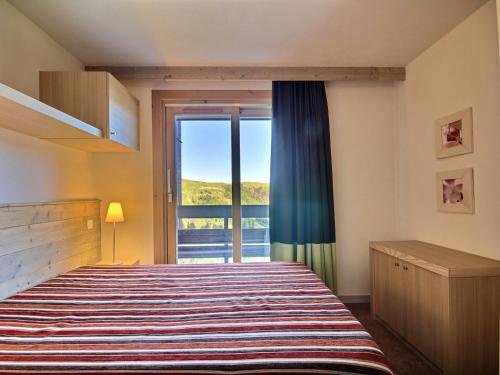 une chambre avec un lit et une grande fenêtre dans l'établissement Deux pièces pour 4-5, balcons, proche des pistes et commerces - FR-1-455-180, à La Plagne Tarentaise