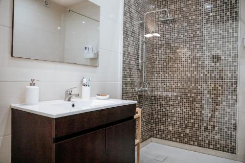a bathroom with a sink and a shower at Rest House - Vila do Conde in Vila do Conde