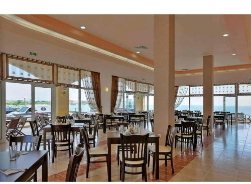 a dining room with tables and chairs and windows at Midia Grand Resort in Aheloy