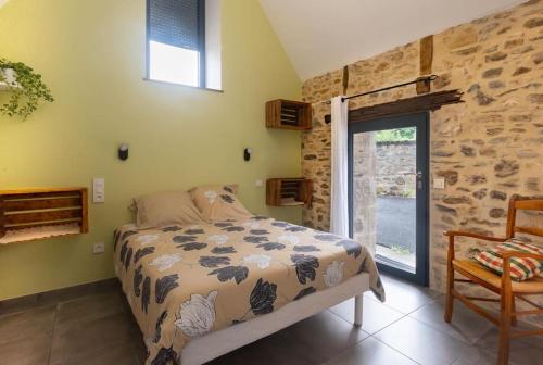 a bedroom with a bed and a stone wall at Le Pamparou, coquette maison au calme in Albussac