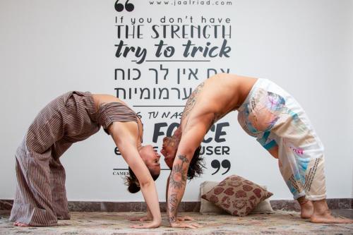 two women doing a yoga pose in front of a wall at Jaal Riad Resort in Marrakech